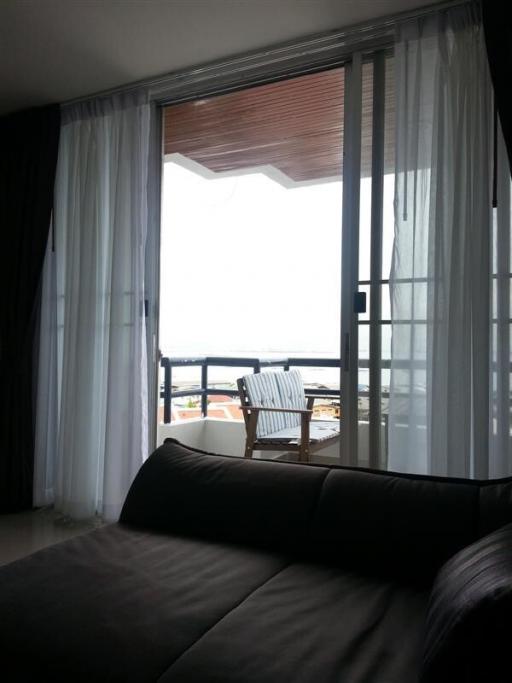 Cozy bedroom with balcony access offering an ocean view