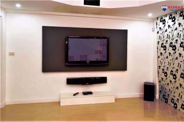 Modern and spacious living room with mounted television and decorative wallpaper