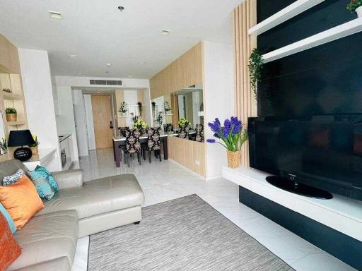 Modern living room with open floor plan featuring a sofa, entertainment unit, and dining area