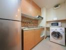 Compact modern kitchen with stainless steel appliances and mosaic backsplash