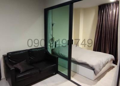Compact bedroom with glass partition, black sofa, and study desk