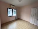 Empty bedroom with pink walls and wooden flooring