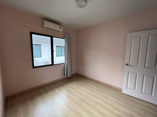 Empty bedroom with pink walls and wooden flooring