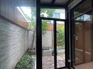 Cozy brick-paved patio with lush plants visible through large glass doors