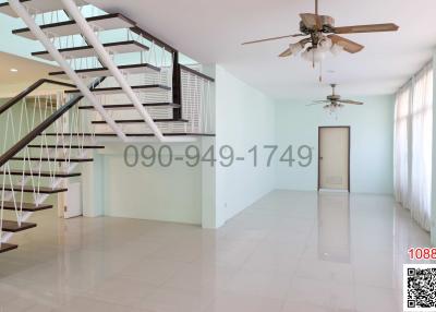 Spacious living room with staircase and ceiling fan