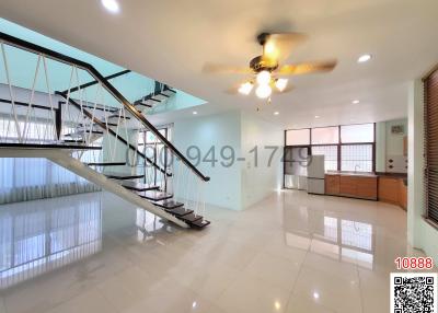 Spacious living room with staircase and ceiling fan
