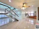 Spacious living room with staircase and ceiling fan