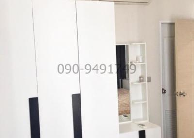 Compact bedroom with a wardrobe, air conditioner, and a glimpse of the bed