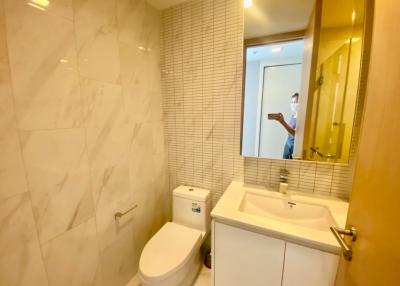 Modern bathroom with marble tiles and well-lit mirror