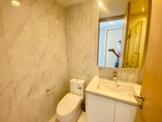 Modern bathroom with marble tiles and well-lit mirror