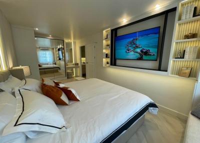 Modern bedroom interior with large bed, flat-screen TV, and mirrored wardrobe