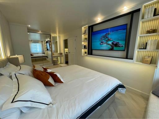 Modern bedroom interior with large bed, flat-screen TV, and mirrored wardrobe