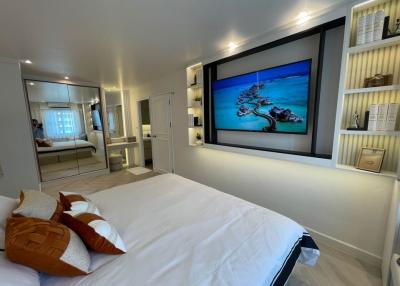 Modern bedroom with a large bed, flat-screen TV, and mirrored closet doors
