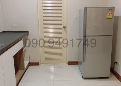 Modern kitchen interior with a refrigerator and white tiled flooring