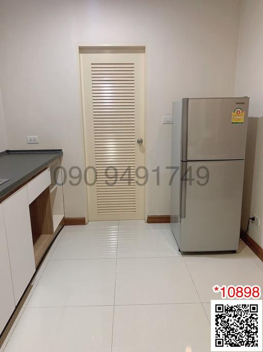 Modern kitchen interior with a refrigerator and white tiled flooring