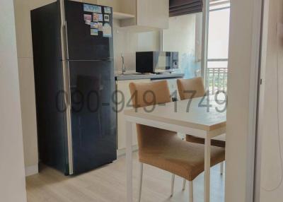 Compact modern kitchen with stainless steel refrigerator and breakfast area leading to balcony