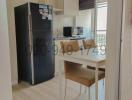 Compact modern kitchen with stainless steel refrigerator and breakfast area leading to balcony