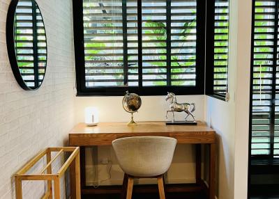 Modern home office interior with a desk, chair, globe, and green shutter window