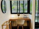 Modern home office interior with a desk, chair, globe, and green shutter window