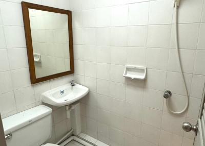 White tiled bathroom with toilet, bidet, mirror, and shower