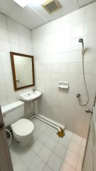 White tiled bathroom with toilet, bidet, mirror, and shower