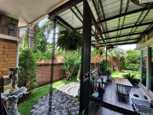 Cozy covered patio with garden view, outdoor furniture, and lush greenery