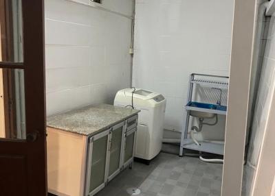 Compact laundry room with tiled flooring, white appliances, and storage space