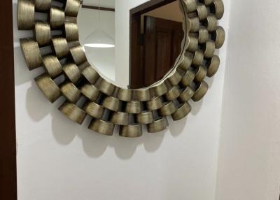 Decorative circular wall mirror in a hallway with a reflection of an interior space
