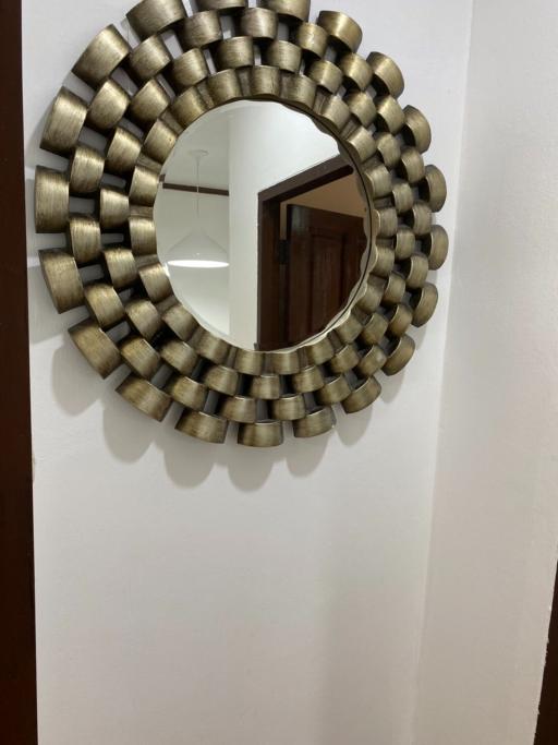 Decorative circular wall mirror in a hallway with a reflection of an interior space
