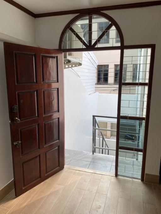 Elegant entrance hall with a wooden arched door and hardwood flooring