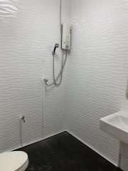 Compact bathroom with white tile walls, electric shower, and a toilet