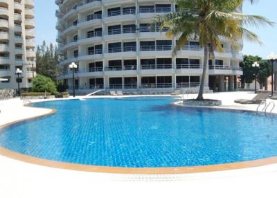 Spacious outdoor pool with lounge chairs and palm trees at a residential building complex