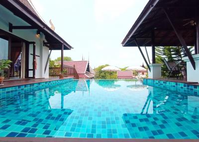 Expansive outdoor swimming pool with surrounding patio and adjacent house