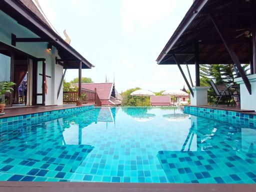 Expansive outdoor swimming pool with surrounding patio and adjacent house