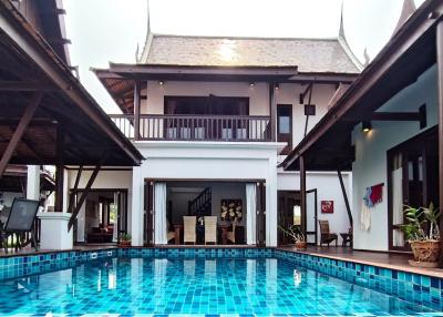 Spacious poolside area with a traditional style building in the background