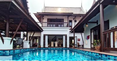 Spacious poolside area with a traditional style building in the background