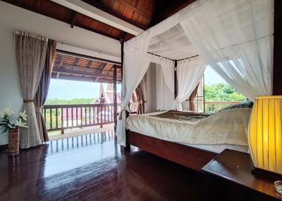 Spacious bedroom with a large bed, canopy, hardwood floors and balcony access