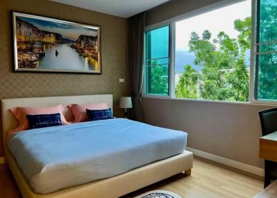 Cozy bedroom with a large bed, artwork, and a view of the greenery