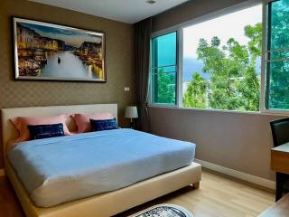 Cozy bedroom with a large bed, artwork, and a view of the greenery