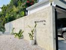 Elegant house exterior with a secure white perimeter wall and lush greenery