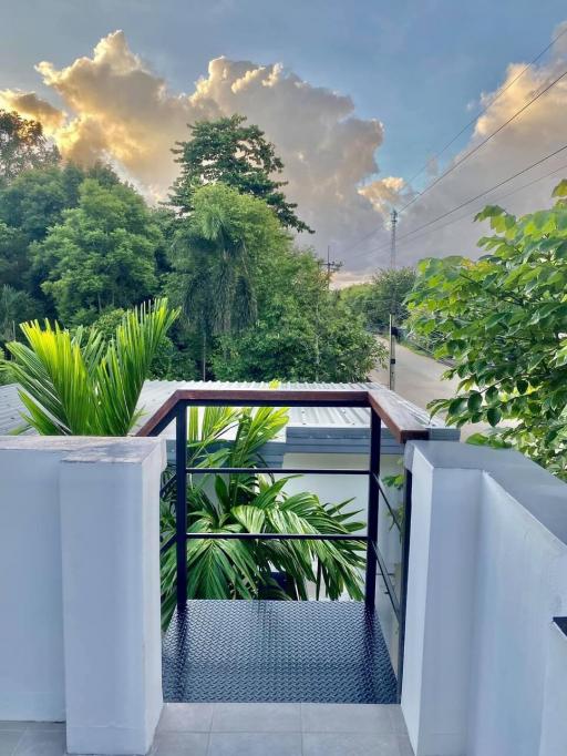 Spacious balcony with a view of greenery and dramatic clouds at sunset