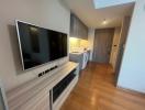 Compact living area with mounted television and adjacent kitchenette