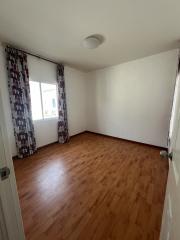 Empty bedroom with hardwood floors and natural light