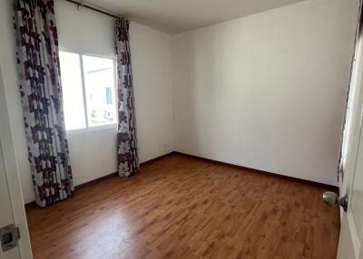 Empty bedroom with hardwood floors and natural light