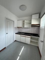 Compact white kitchen with floral tile backsplash and gray tile flooring