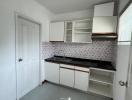 Compact white kitchen with floral tile backsplash and gray tile flooring