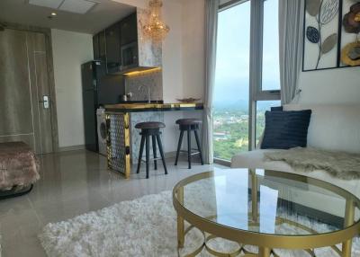 Contemporary open-plan living room with kitchenette, showcasing modern furniture and a scenic view