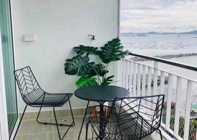 Cozy balcony with ocean view, seating arrangement, and decorative plant