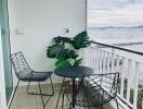 Cozy balcony with ocean view, seating arrangement, and decorative plant