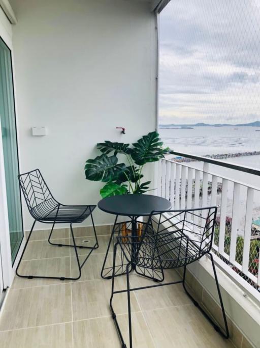 Cozy balcony with ocean view, seating arrangement, and decorative plant